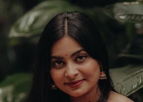 pexels-photo-33338138-33338138 Beautiful portrait of a woman in traditional attire set against lush green leaves outdoors.